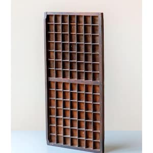 May include: A vintage wooden printer's tray with numerous small, square compartments. The tray is made of dark brown wood and has a rectangular shape. It is designed for organizing small items or displaying collectibles.