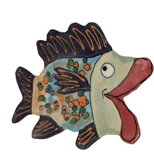 May include: A ceramic fish dish with a blue, green, orange, and black speckled design. The fish has a wide open mouth and a large, white eye.