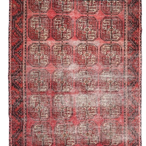 May include: A rectangular red rug with a repeating geometric pattern in black and beige. The rug has a detailed border with a similar design. The rug's design is symmetrical and the rug appears to be vintage.