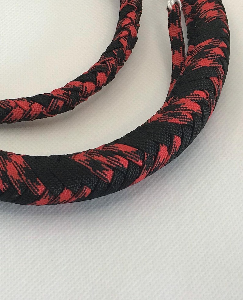 May include: A braided whip with a black and red checkered pattern. The whip is made of a thick, durable material and is designed for use in a variety of settings.