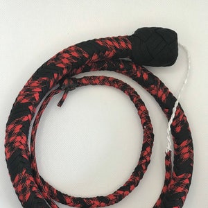 May include: A black and red braided whip with a black knotted handle. The whip is coiled and ready for use.