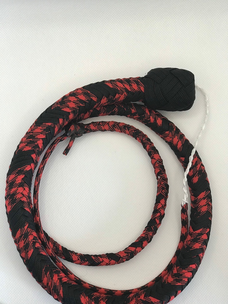 May include: A black and red braided whip with a black knotted handle. The whip is coiled and ready for use.