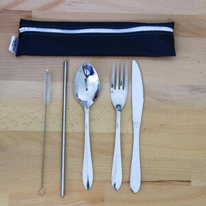 Può includere: Una custodia nera con cerniera e una striscia bianca, contenente un cucchiaio, una forchetta, un coltello e una cannuccia in acciaio inossidabile con uno spazzolino per la pulizia.