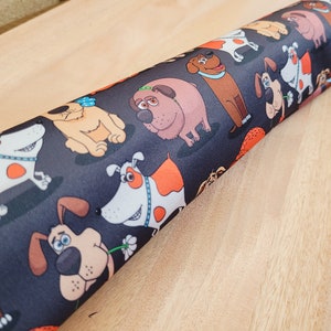 May include: Black fabric with a repeating pattern of cartoon dogs in various poses. The dogs are brown, white, and orange with black outlines.
