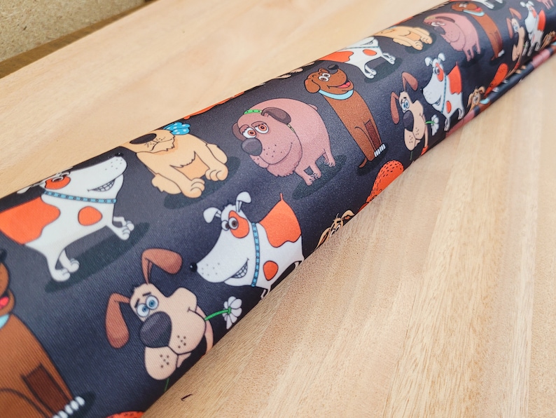 May include: Black fabric with a repeating pattern of cartoon dogs in various poses. The dogs are brown, white, and orange with black outlines.