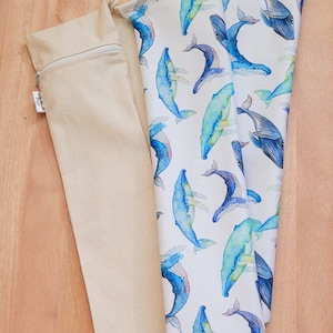 May include: A white fabric bag with a blue whale pattern. The bag is folded and has a drawstring closure. The bag is made of cotton and is perfect for carrying small items.