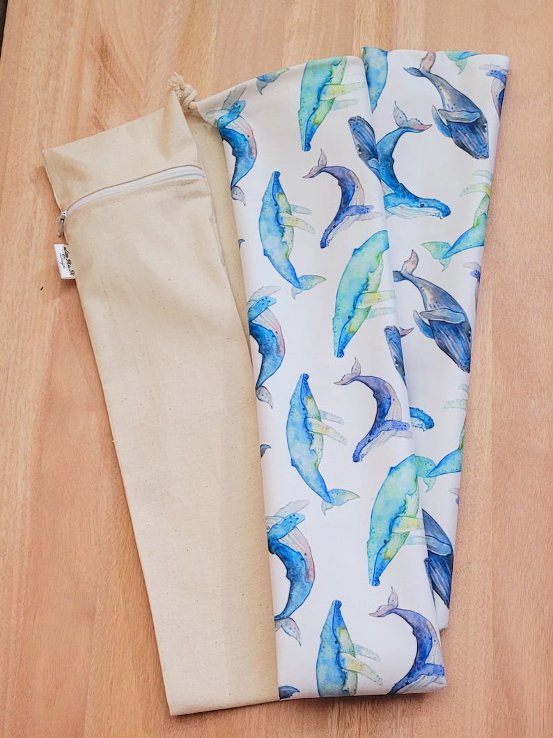 May include: A white fabric bag with a blue whale pattern. The bag is folded and has a drawstring closure. The bag is made of cotton and is perfect for carrying small items.