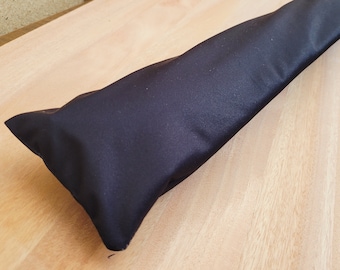 May include: A black fabric storage bag or pouch, lying on a wooden surface.