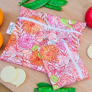 May include: Two reusable zippered bags with a floral print in shades of pink, orange, and green. The bags are made of a white fabric with a floral pattern. The text "Love Your Planet" is printed on the larger bag.
