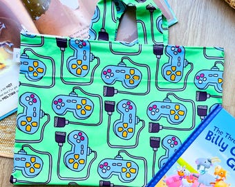 May include: A green tote bag with a repeating pattern of blue video game controllers and cords. The bag has a handle and is made of fabric.
