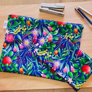 Può includere: Due pochette con cerniera con sfondo blu e un motivo floreale con fiori rosa, rossi, gialli e verdi brillanti. Le pochette sono in tessuto e hanno una chiusura a zip.