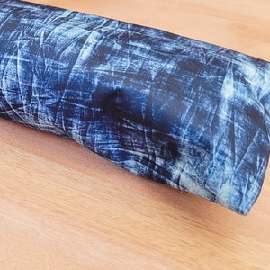 May include: A blue and white denim-patterned fabric pillow. The pillow is rectangular and has a soft, plush texture.