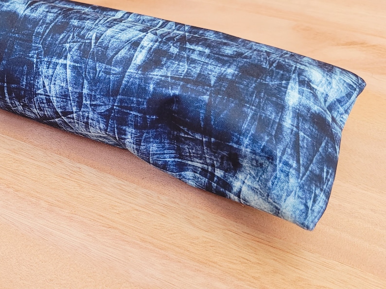 May include: A blue and white denim-patterned fabric pillow. The pillow is rectangular and has a soft, plush texture.