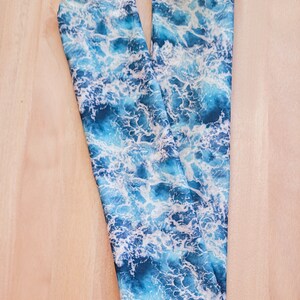 May include: A blue and white fabric with a wave pattern. The fabric is folded in half and is lying on a wooden surface.