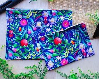 Pode incluir: Duas bolsas com zíper com uma estampa floral em um fundo azul. A estampa apresenta flores e folhas rosa, vermelhas, amarelas e brancas. As bolsas são feitas de um tecido durável e são perfeitas para guardar pequenos itens.