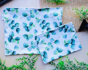 Pode incluir: Duas bolsas reutilizáveis com fecho de correr brancas com um padrão de folhas de eucalipto verdes. As bolsas são feitas de um tecido resistente à água e são perfeitas para guardar comida, artigos de higiene pessoal ou outros artigos pequenos.
