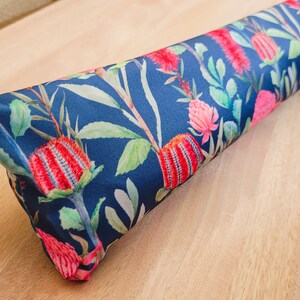 May include: A blue fabric doorstop with a floral pattern featuring red and pink flowers and green leaves.