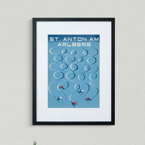 May include: A black framed poster with a blue background and white ski trails. The poster reads "ST. ANTON AM ARLBERG".