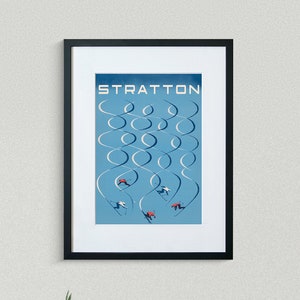 May include: A framed poster with a blue background and white ski trails. The poster says "Stratton" at the top and features skiers on the trails.