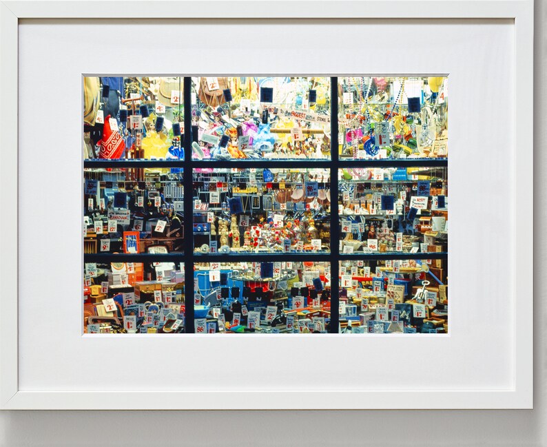 May include: A shop window display filled with a variety of small items, including toys, trinkets, and other miscellaneous goods. The items are arranged in a grid pattern and are all tagged with price labels.