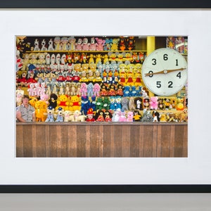 May include: A wall of colorful stuffed animals, including bears, dogs, and other creatures, with a large clock face behind them. The clock face has a white background with black numbers and a wooden pointer.