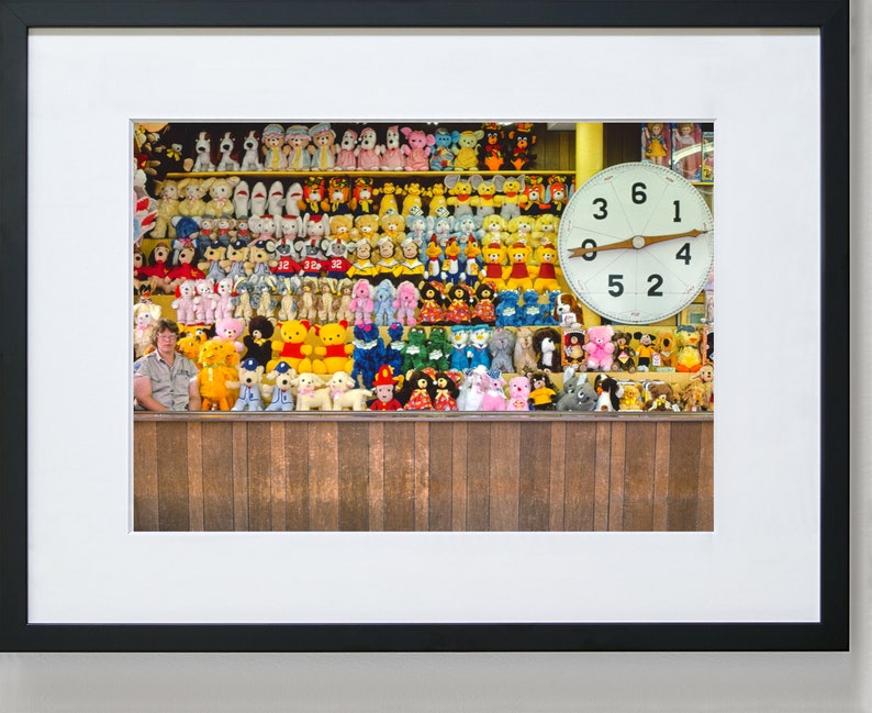 May include: A wall of colorful stuffed animals, including bears, dogs, and other creatures, with a large clock face behind them. The clock face has a white background with black numbers and a wooden pointer.