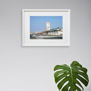 May include: A vintage photograph of a building with a sign that reads "Hunt's Pier Putting Golf" in red letters. The building is located on a boardwalk with a blue sky in the background.