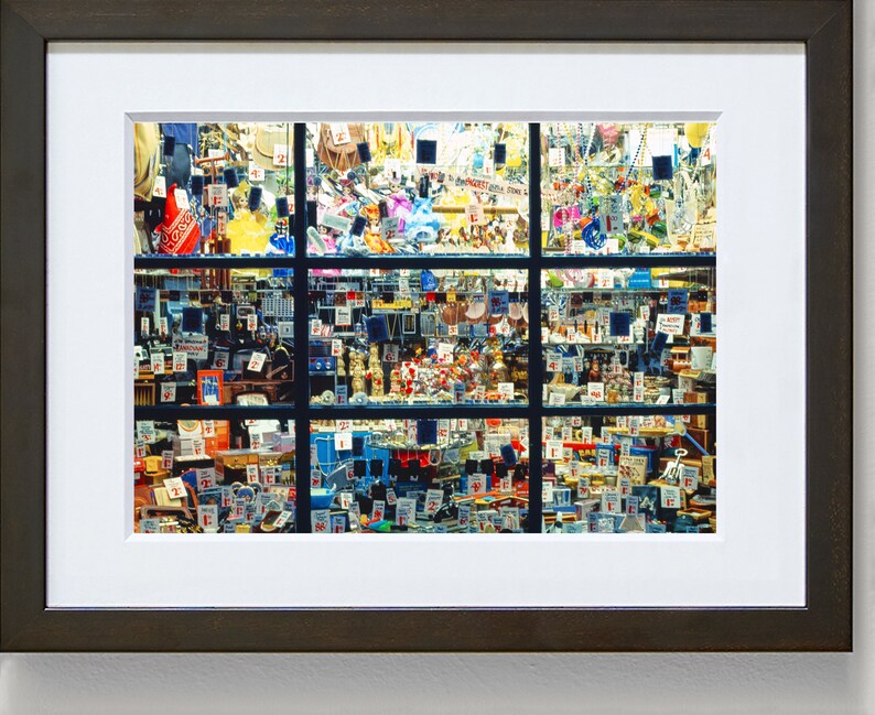 May include: A shop window display filled with a variety of items for sale. The window is divided into nine sections, each filled with a variety of colourful objects. The items include small toys, trinkets, and other miscellaneous goods. Many of the items have price tags attached to them.