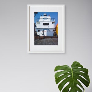 May include: A framed photograph of a white boat docked at a pier. The boat has a white cabin with a red and white sign that reads "Sea Boat".