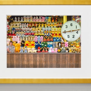May include: A carnival game with a large clock face and a variety of stuffed animals. The clock face has the numbers 1, 2, 3, 4, 5, and 6. The stuffed animals are mostly in shades of pink, yellow, and blue.