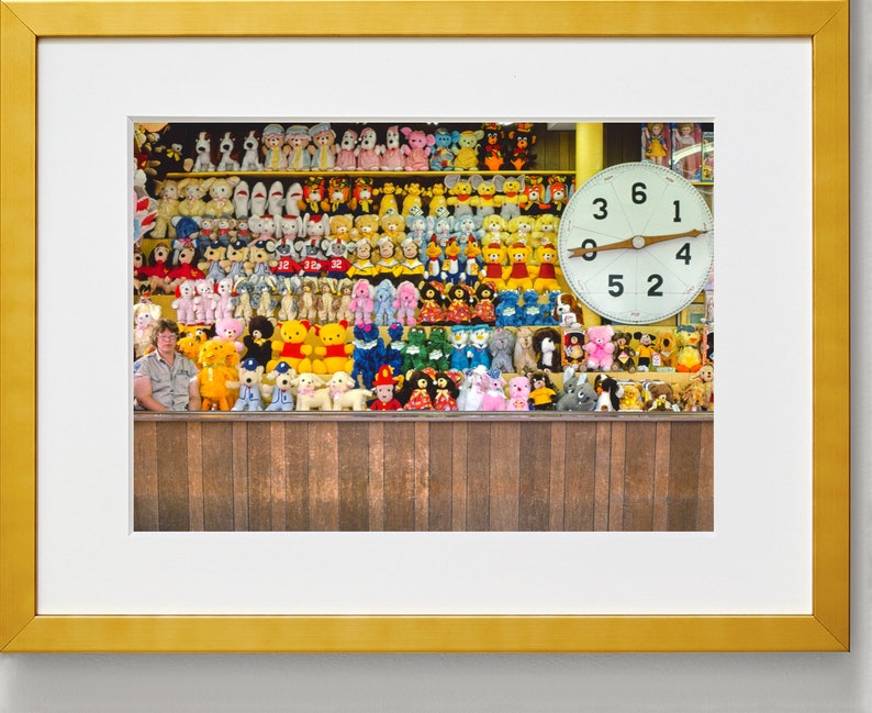 May include: A carnival game with a large clock face and a variety of stuffed animals. The clock face has the numbers 1, 2, 3, 4, 5, and 6. The stuffed animals are mostly in shades of pink, yellow, and blue.