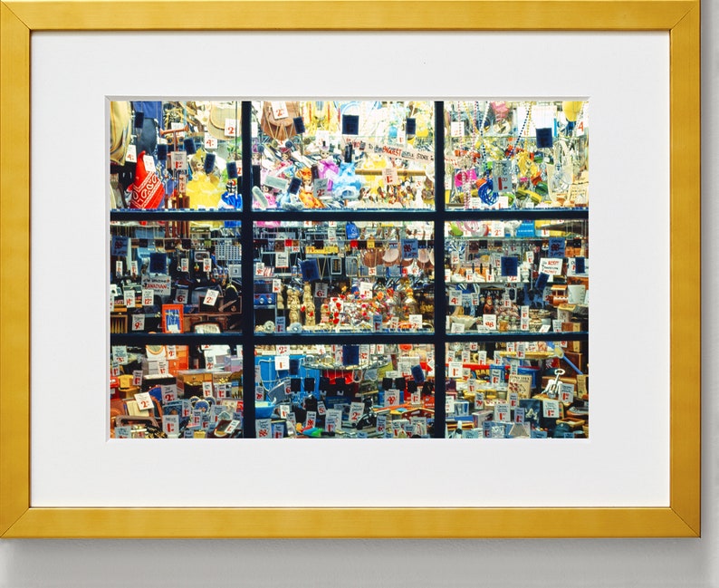 May include: A shop window display filled with a variety of colourful items, including toys, trinkets, and other small goods. The window is divided into nine sections, each filled with different items. The items are all tagged with price labels.