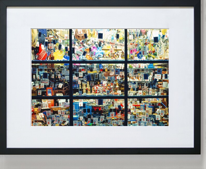May include: A shop window display featuring a wide variety of items, including jewellery, toys, and other trinkets. The items are arranged in a grid pattern and displayed on shelves and in cases. Many of the items have price tags attached.