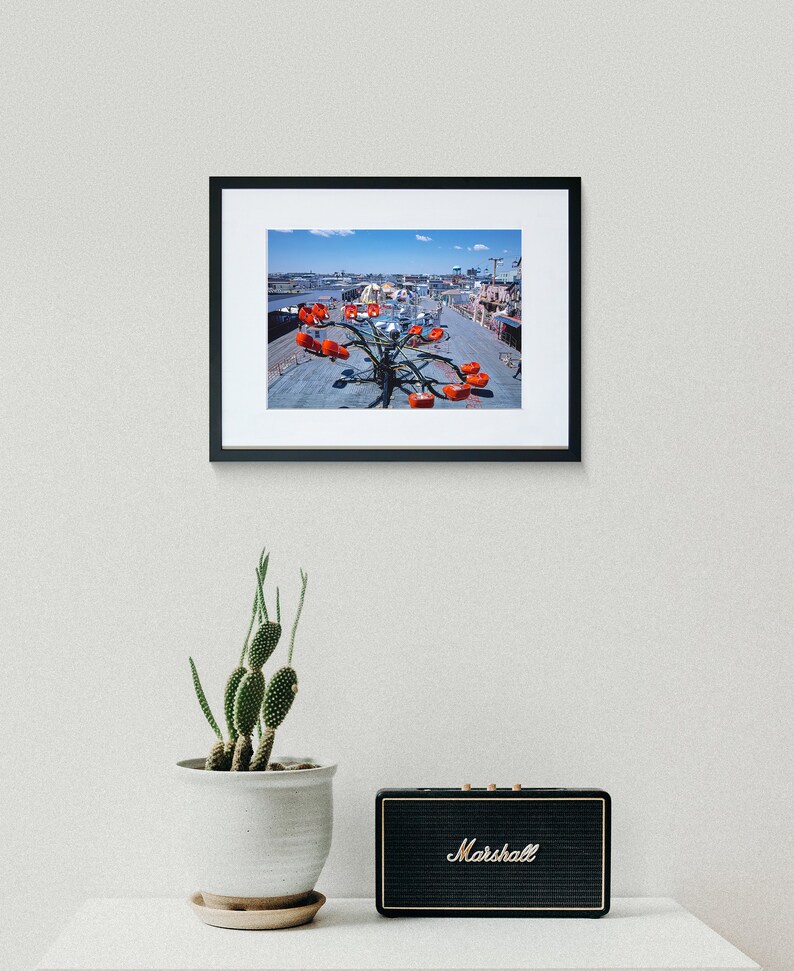 May include: A framed photograph of a red and silver amusement park ride with a blue sky in the background.