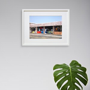 Pode incluir: Uma fotografia emoldurada de uma vitrine com uma marquise vermelha, azul e verde. A vitrine tem v&aacute;rias janelas e uma placa que diz "Bem-vindo".