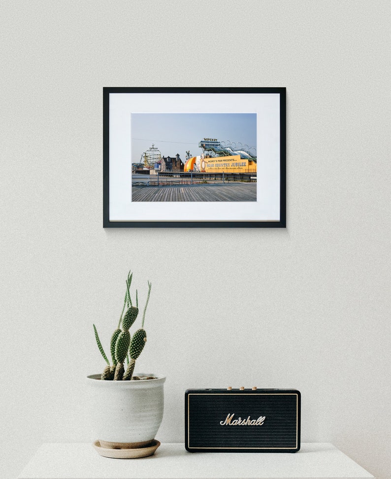 May include: A framed photograph of a yellow and orange amusement park ride with the text "Whirly's Fun Presents - Old Country Jubilee" on a wooden boardwalk.