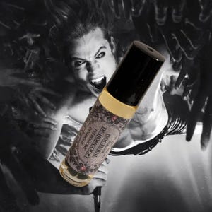May include: A cylindrical glass roller bottle with a black cap and a gold band. The label features ornate floral borders and the text Nocturne De Lioncourt Pheromone Cologne. The bottle is positioned against a dark, monochromatic background.