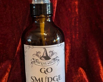 Pode incluir: Uma garrafa de vidro marrom com um borrifador preto e um rótulo branco que diz "THE LOVE WITCHE GO SMUDGE YOURSELF! PALO SANTO SWEETGRASS SAGE SMUDGE SPRAY 4OZ"