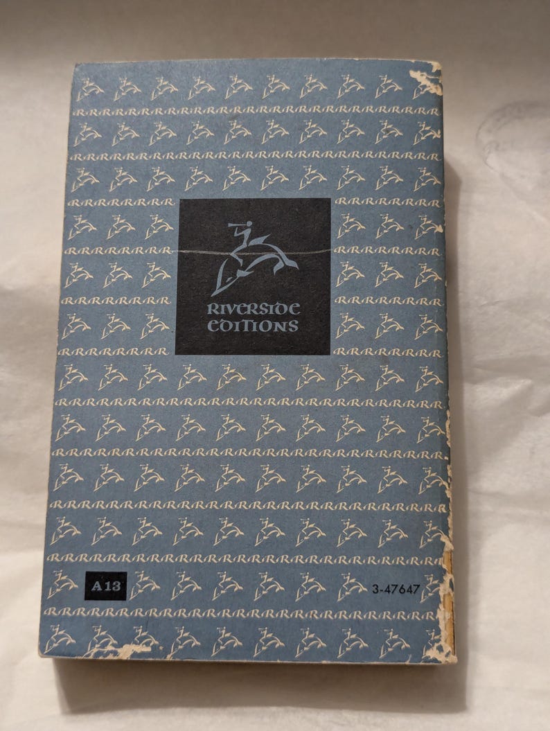Op de afbeelding: Achterkant van een vintage boek met een lichtblauwe achtergrond en een patroon van herhaalde 'R'-tekens. Een zwart vierkant toont de tekst "Riverside Editions" en een springend hertenlogo. De randen van het boek zijn beschadigd.