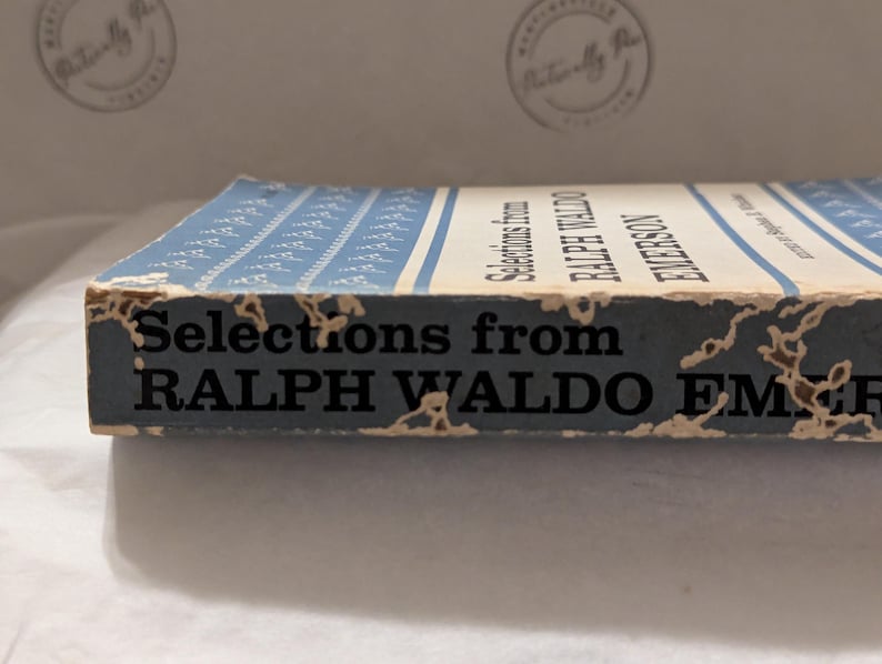 Op de afbeelding: Een vintage boek getiteld "Selections from Ralph Waldo Emerson". Het boek heeft een blauw-witte omslag met een patroon. De rug toont de titel en de naam van de auteur in zwarte tekst. De randen vertonen tekenen van slijtage.