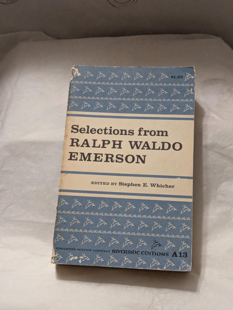 Op de afbeelding: Een vintage boek getiteld "Selections from Ralph Waldo Emerson" met een lichtblauwe omslag met een herhalend patroon van gestileerde vogels. De titel van het boek en de naam van de auteur staan prominent in vette, zwarte letters. Het boek maakt deel uit van de Riverside Editions-serie.