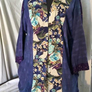 May include: A long, blue and purple kimono with a floral pattern featuring white cranes and gold accents. The kimono has a V-neck and long sleeves.