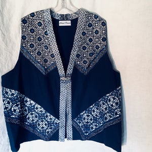 May include: A navy blue sleeveless vest with a white and blue geometric pattern. The vest has a V-neck and a button closure. The label "Cloud Dance" is visible on the front of the vest.