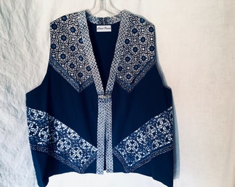May include: A navy blue sleeveless vest with a white and blue geometric pattern. The vest has a V-neck and a button closure. The label "Cloud Dance" is visible on the front of the vest.