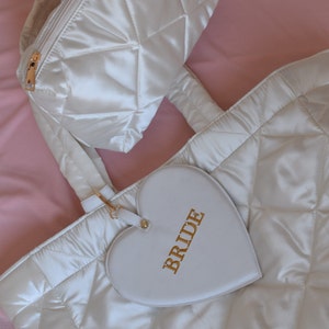White satin quilted bride tote and matching pouch laid flat, minimal background, elegant wedding gift for bride.