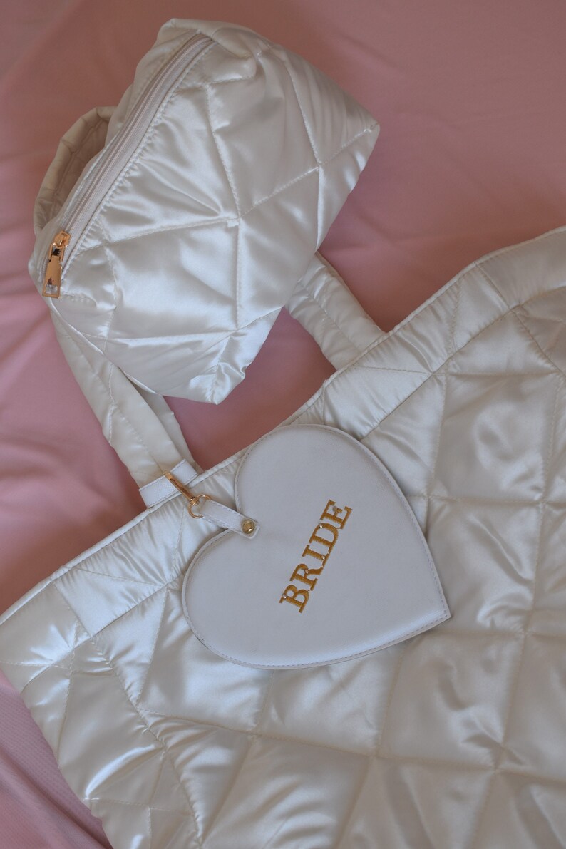 White satin quilted bride tote and matching pouch laid flat, minimal background, elegant wedding gift for bride.