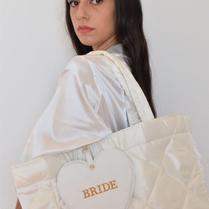 White bride tote bag in wedding preparation setting, quilted satin with pouch, perfect for wedding morning essentials.