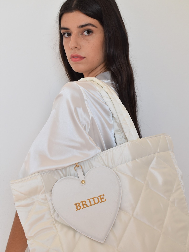 White bride tote bag in wedding preparation setting, quilted satin with pouch, perfect for wedding morning essentials.