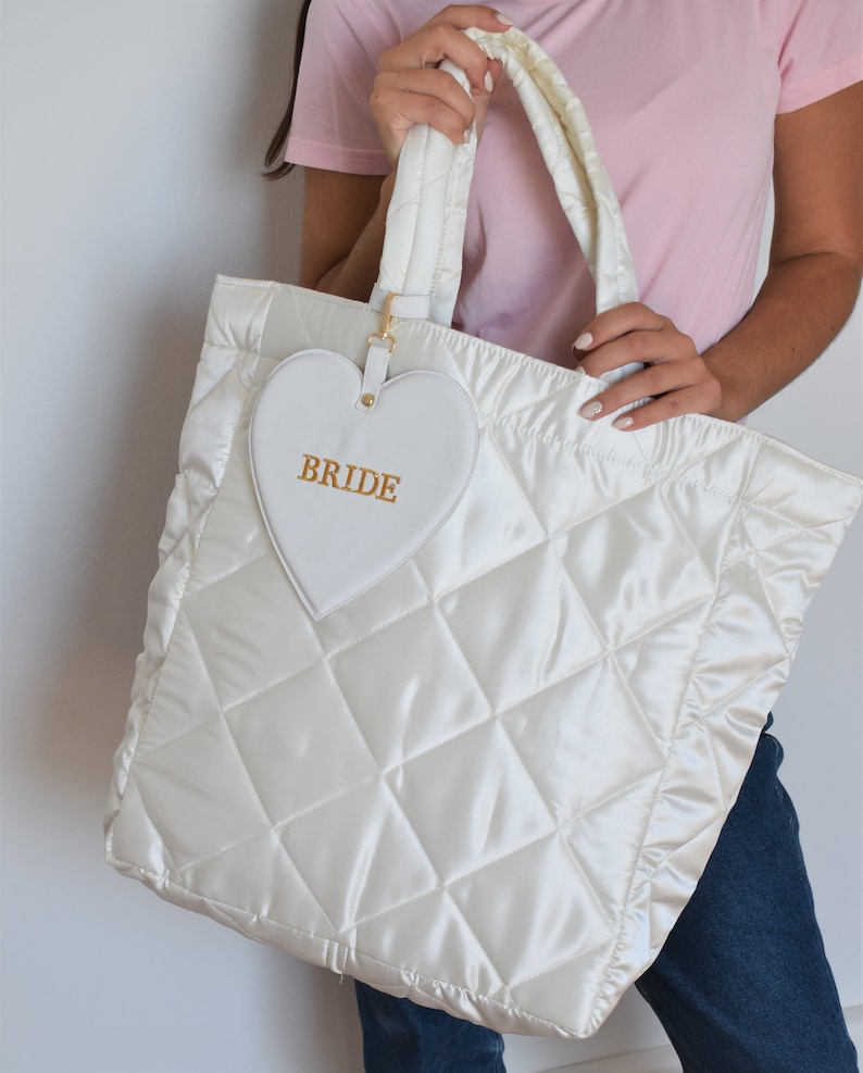 White bride tote bag in wedding preparation setting, quilted satin with pouch, perfect for wedding morning essentials.