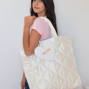 White bride tote bag in wedding preparation setting, quilted satin with pouch, perfect for wedding morning essentials.